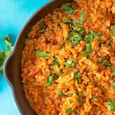 mexican rice with cilantro and parsley in a skillet on a blue surface