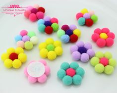 several different colored pom poms on a white plate with a pink button in the middle