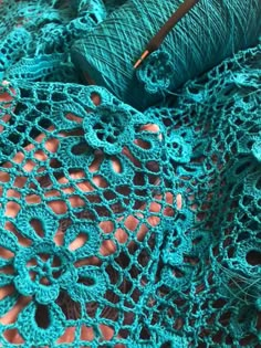 yarn and crochet are laying on top of each other in shades of teal