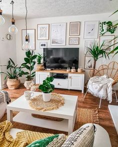 a living room filled with lots of furniture and plants on top of tables in front of a flat screen tv