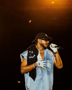 a man in blue vest and white gloves singing into a microphone on stage at night