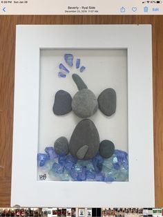 an image of a rock and sea glass in a white frame with blue rocks on it