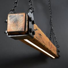 a wooden object suspended from chains on a black background