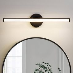 a round mirror on the wall above a table with a potted plant in it