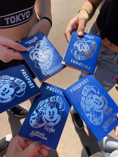 four people holding up blue disney passports