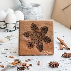 a wooden block with an intricate design on it next to some nuts and cinnamons