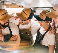 a group of people standing around each other wearing hats and aprons on their heads