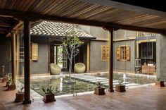 an indoor courtyard with potted plants and water features in the center, surrounded by wooden pillars