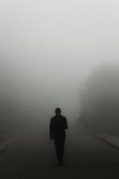 a man walking down a street in the fog