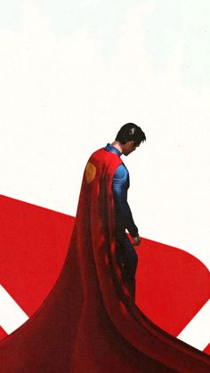 a man in a superman costume standing on top of a red and white plane with his cape over his head