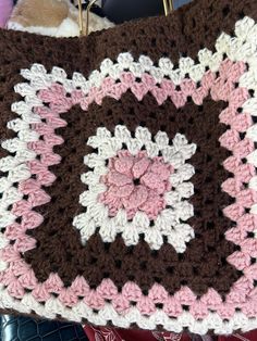 a crocheted blanket with pink, brown and white squares