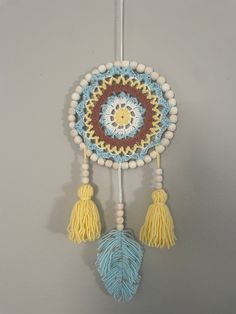 a crocheted wall hanging with tassels and beads in the shape of a circle