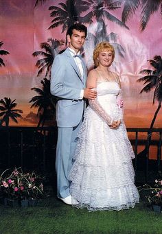 a man and woman posing for a photo in front of a palm tree backdrop at their wedding