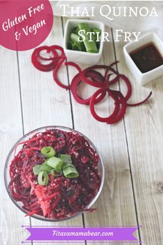 a glass bowl filled with red cabbage and green onions next to other dishes on a wooden table