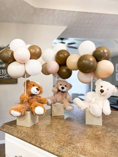 three teddy bears sitting on top of boxes with balloons