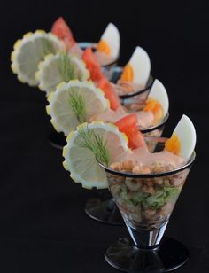 a row of glasses filled with different types of food on top of a black table