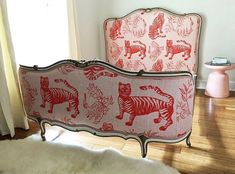 a bed with red and white tiger designs on the headboard next to a window