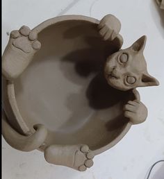 a clay sculpture of a cat in a bowl