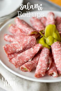 salami rolls on a white plate with green peppers