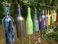 many different colored bottles are hanging from a line in the grass with beads attached to them