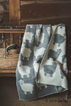 a blanket with sheeps on it sitting next to a basket and wooden flooring