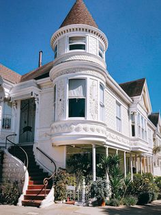 a large white victorian style house with stairs leading up to it