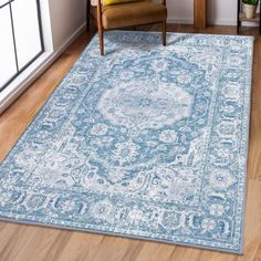 a large blue rug with an ornate design on the floor in front of a chair