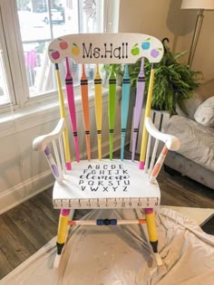 a colorful wooden chair sitting on top of a table next to a ruler and potted plant