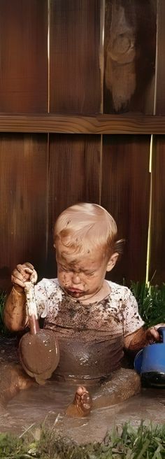 a statue of a boy sitting in the grass next to a blue potted plant