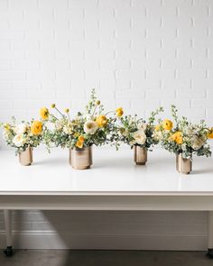 four gold vases filled with yellow and white flowers