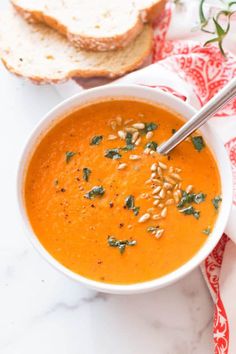 a bowl of tomato soup with bread on the side