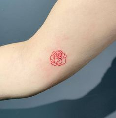 a small red rose tattoo on the arm