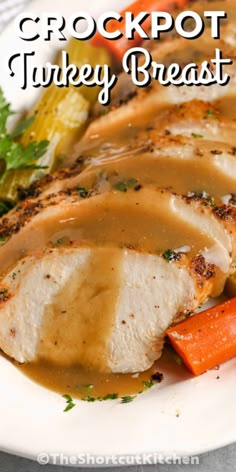 a white plate topped with meat covered in gravy and carrots next to a salad