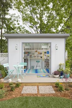 a small white shed with a pool in the back ground and tables on the side