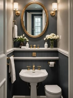 a white toilet sitting next to a bathroom sink under a round mirror in a bathroom