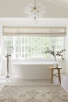 a white bathroom with a large rug on the floor and a bathtub in the corner