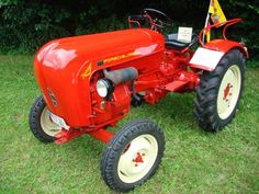 an old red tractor parked in the grass