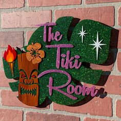 the tiki room sign is made out of wood and glittery green paint on a brick wall