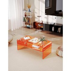 an orange coffee table sitting on top of a hard wood floor next to a window