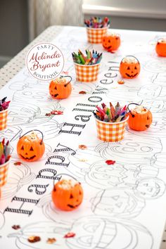 there are many pumpkins on the table with pencils and markers in each cup