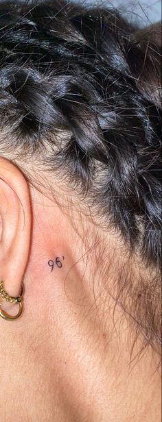 a woman's ear has a small tattoo on it