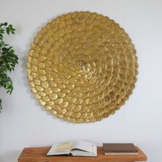 a book is sitting on a wooden table next to a gold wall decoration with a spiral design