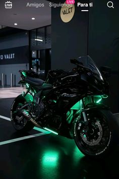 a black motorcycle parked in a parking lot with green lights on it's side