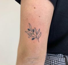 a woman's arm with a small black and white leaf tattoo on her left arm