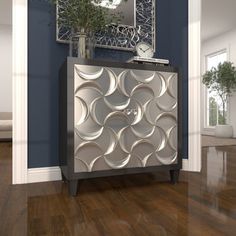 a silver cabinet sitting on top of a hard wood floor next to a mirror and potted plant