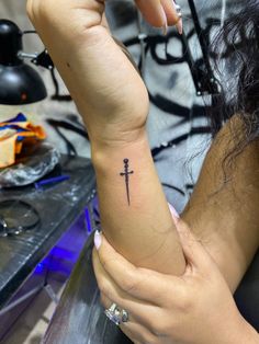 a woman's arm with a cross tattoo on it