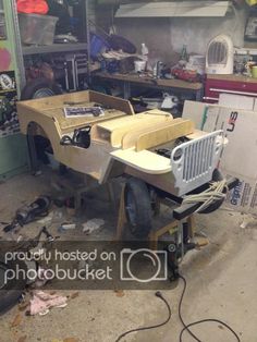 an old jeep is being worked on in a garage with tools and other items around it