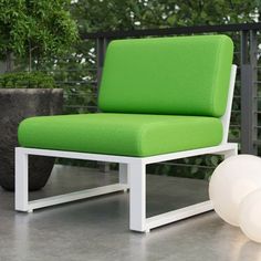 a green and white chair sitting on top of a cement floor next to a potted plant