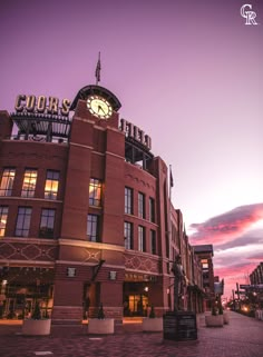 a large building with a clock on the top and an illuminated sign above it at dusk