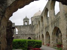 an old building with arches and flowers in the foreground